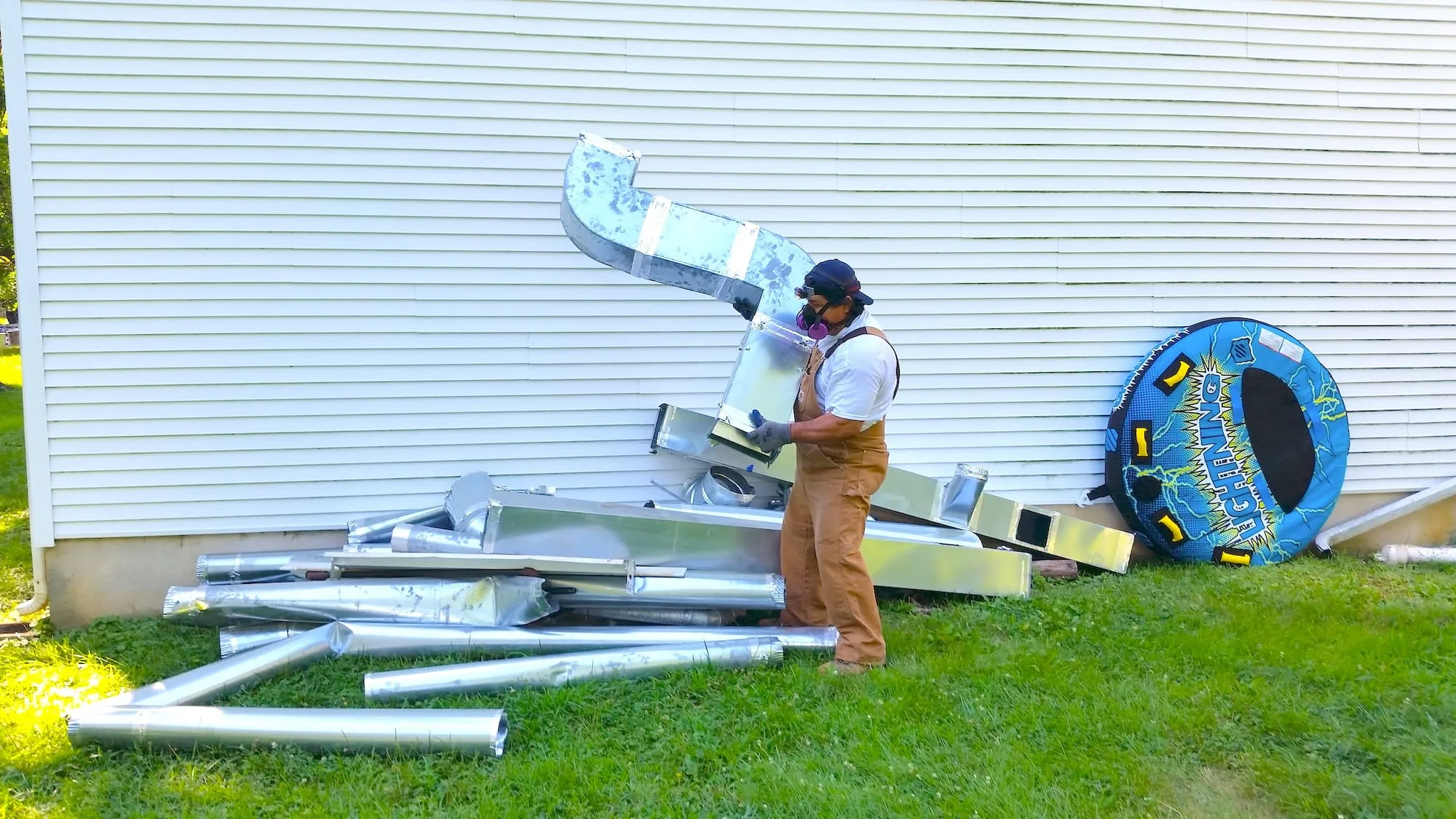 Worker moving salvaged metal ductwork for Second Chance, Inc., a Baltimore non-profit. This pile of secondhand HVAC and used building materials offers affordable, sustainable options for home improvement projects.
