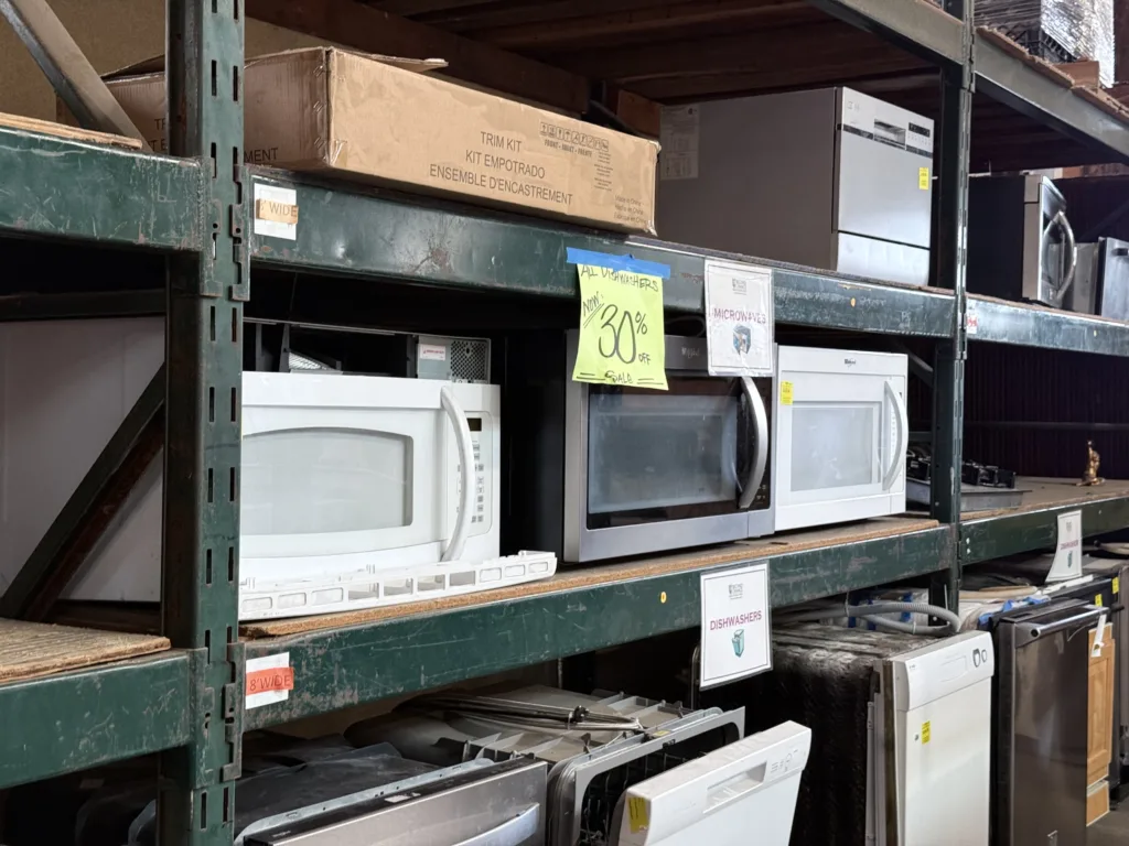 Warehouse shelves packed with affordable secondhand microwaves and used dishwashers on sale at Second Chance, a Baltimore non-profit dedicated to salvaging home improvement items.
