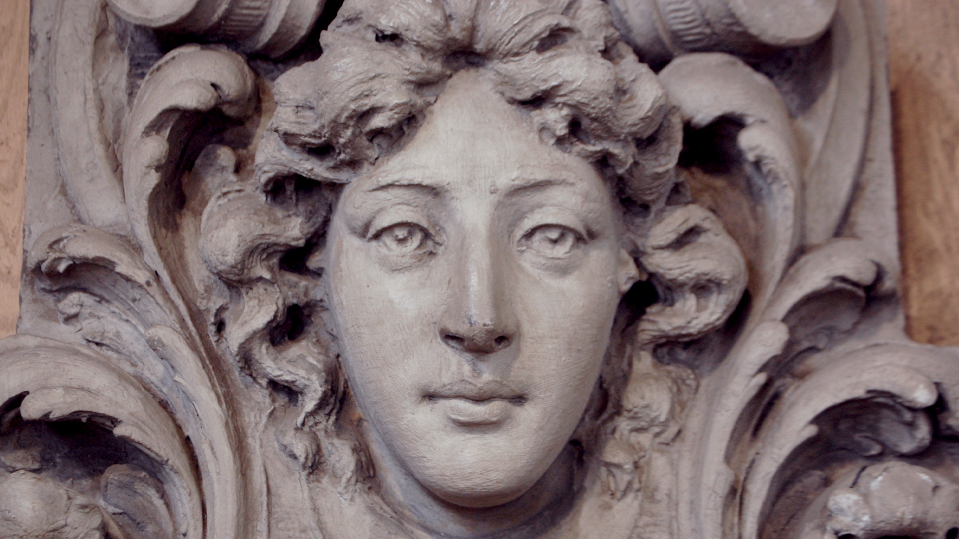 Salvaged antique decorative carving of a classical woman's face with ornate scrollwork, a unique secondhand find for vintage home decor.
